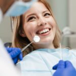 Une jeune femme sourit à son dentiste lors de son examen bucco-dentaire