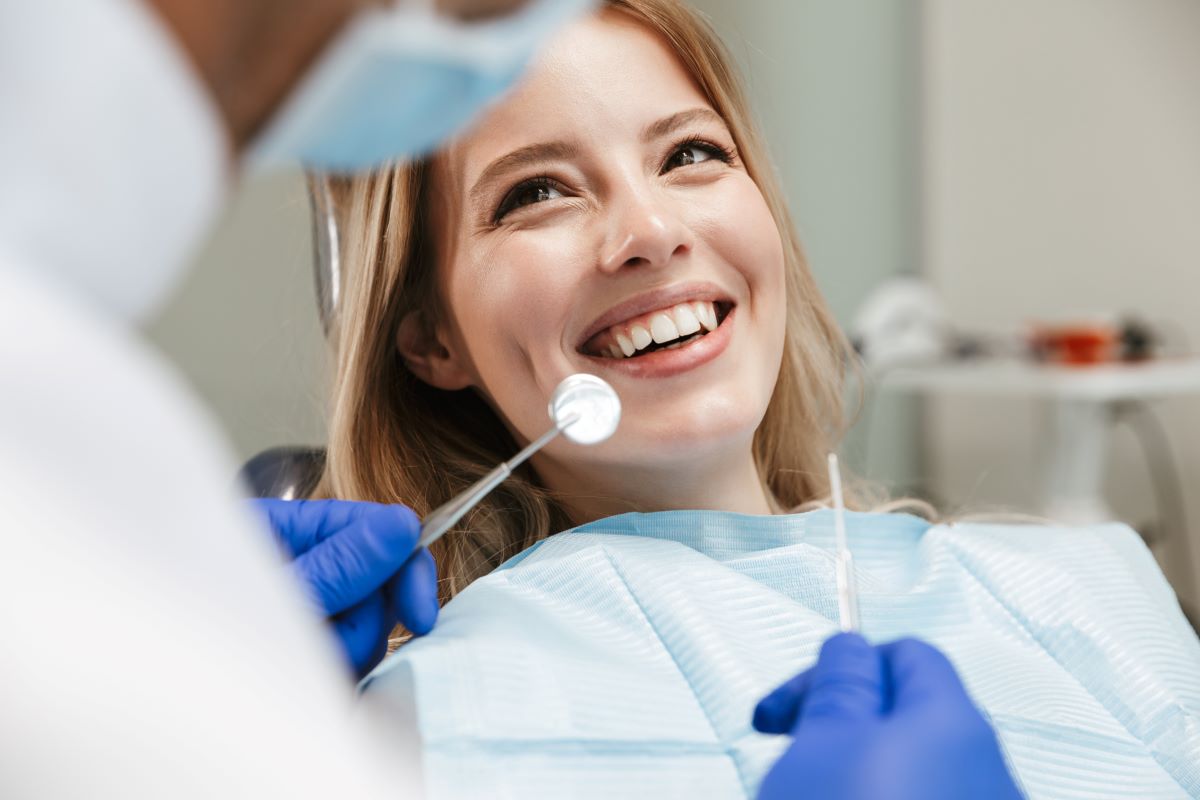Une jeune femme sourit à son dentiste lors de son examen bucco-dentaire